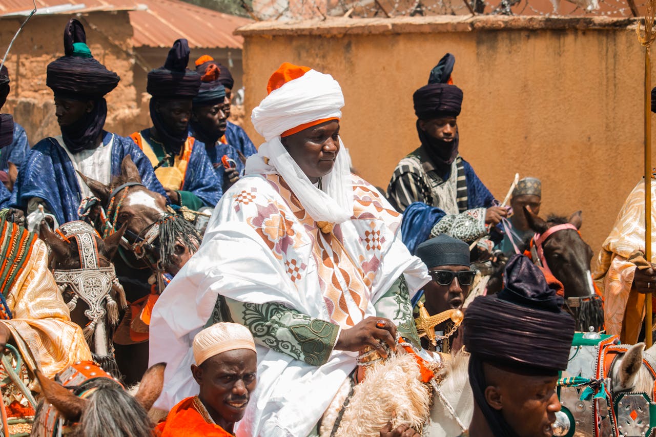 services-02 Vibrant scene from a traditional Hausa festival with attendees in colorful attire, on horseback.